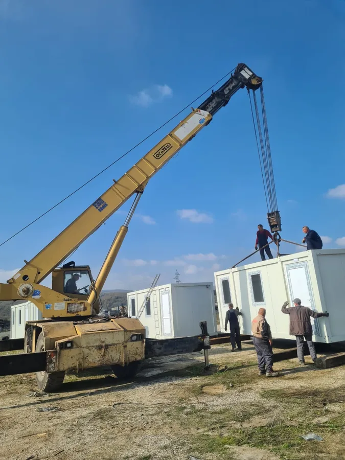 Mobile crane lifting a prefabricated cabin into place on site