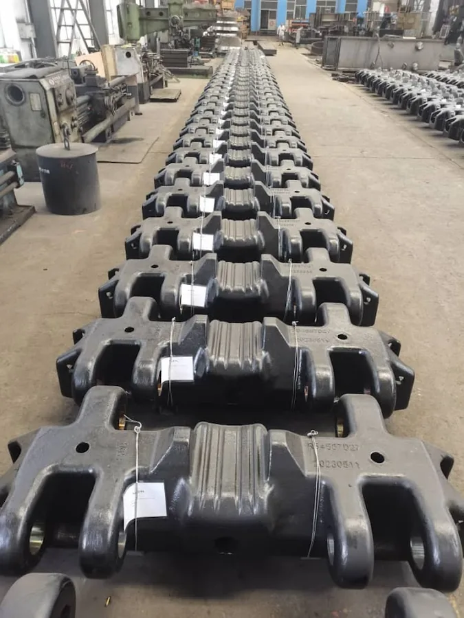 Row of cast excavator track pads laid out in the workshop
